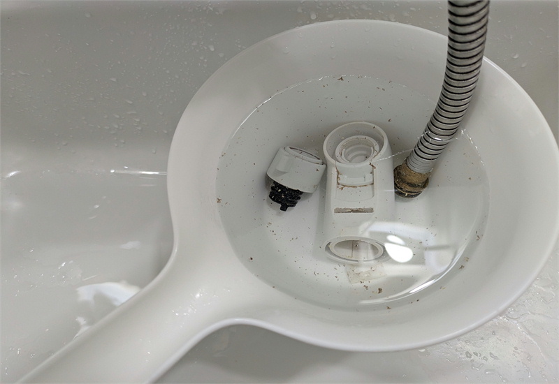 分解した蛇口パーツを洗面器でつけ置きして汚れを浮かせている様子