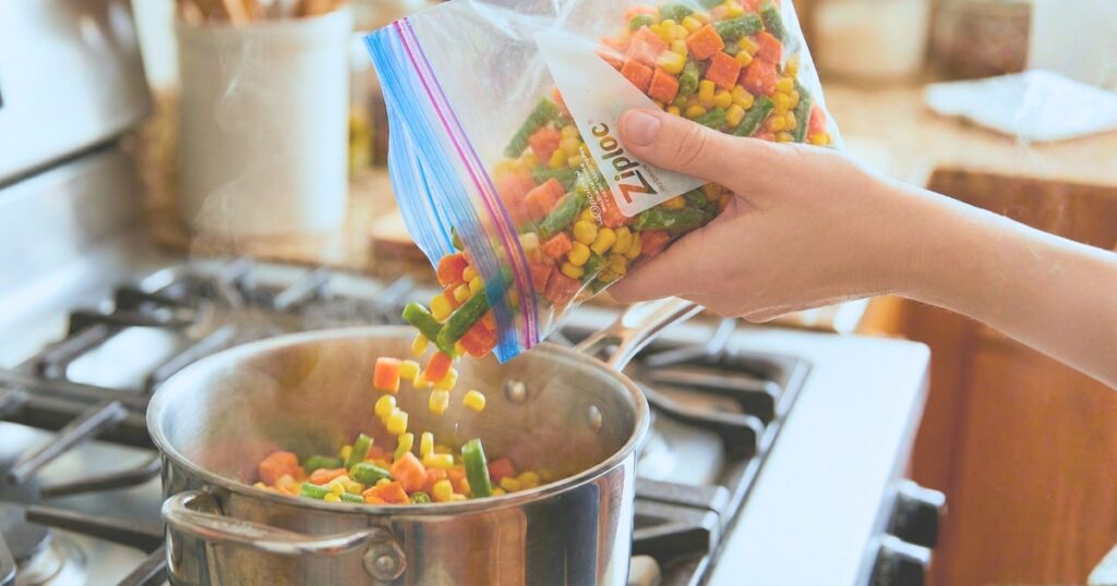 冷凍したミックス野菜を解凍せずそのまま鍋に入れて調理している様子